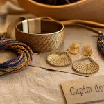Bijoux brésiliens tressés et capim dourado sur lin beige, gros plan.